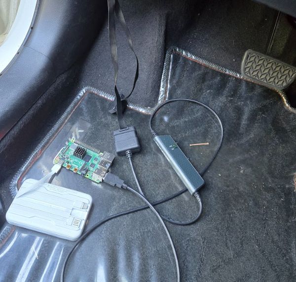 車內腳踏墊上的實車擷取設備：Kvaser Leaf Light HS v2 經 OBD-II 接頭連到 Raspberry Pi 4B，由行動電源供電